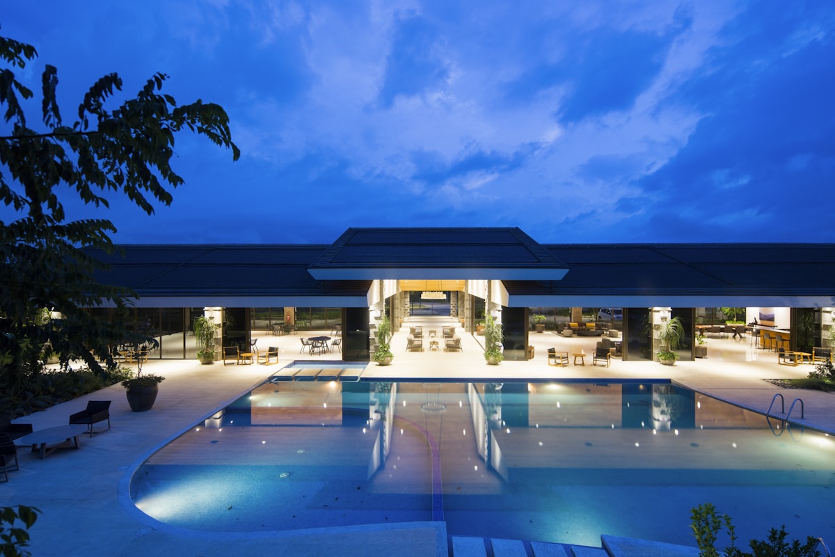 An illuminated luxury lodge and infinity pool at dusk